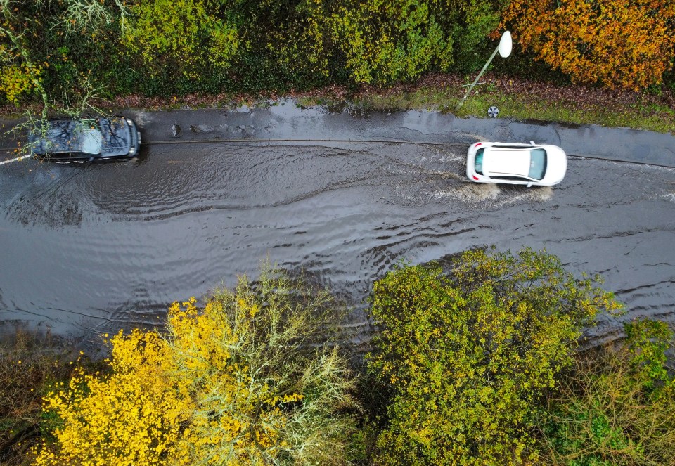 Cars create a splash as they forge a path through flood water on a road in Chandler’s Ford near Southampton, Hants, this morning