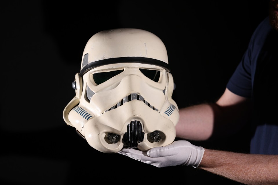 a person holding a storm trooper helmet in their hand