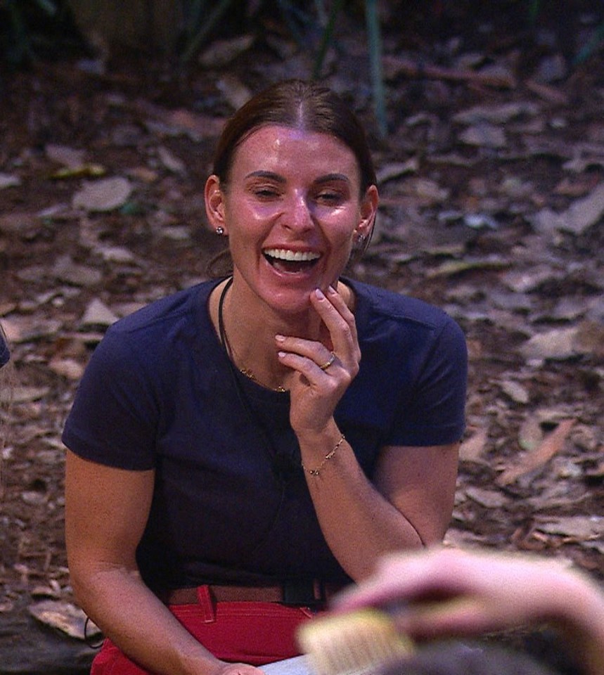 two women are sitting on the ground laughing and one is holding a water bottle