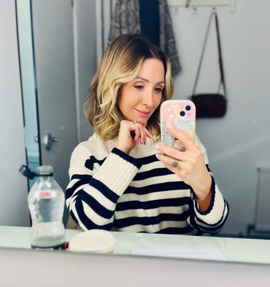 a woman in a striped sweater is taking a selfie in front of a mirror