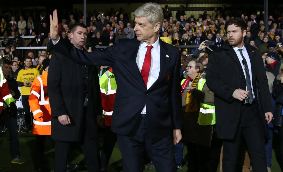 a man in a suit and tie waves to the crowd