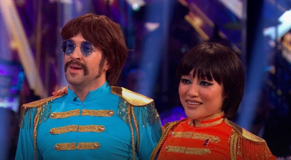 a man and a woman are standing next to each other with a bbc logo in the background