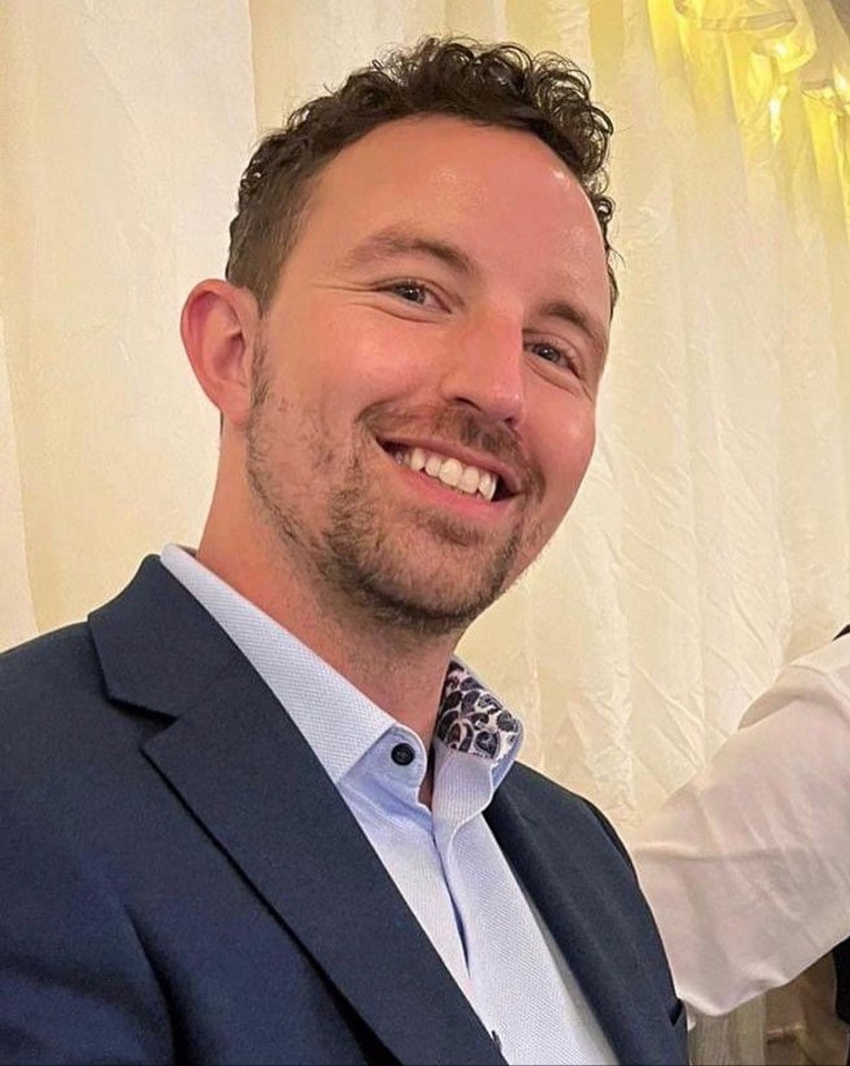 a man in a suit and white shirt smiles for the camera