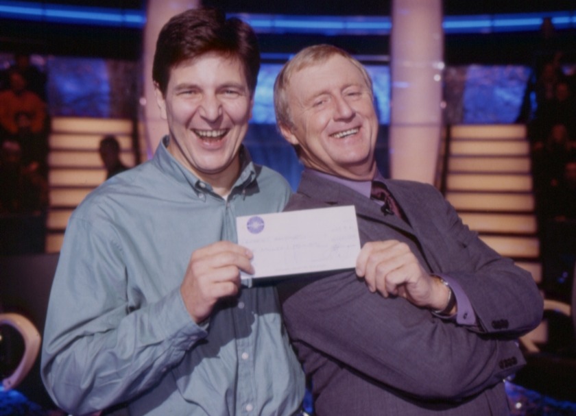 two men are posing for a picture and one of them is holding a check with a nasa logo on it