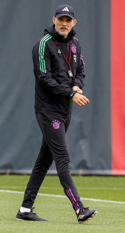 a man wearing a black adidas jacket walks on a field