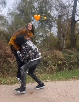 a man is carrying a woman on his back on a dirt road .