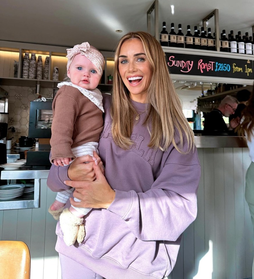 a woman holding a baby in front of a sign that says sunday roast