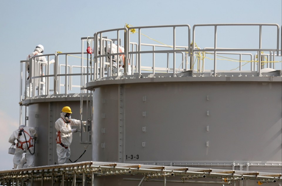 Workers paint new storage tanks holding radioactive water