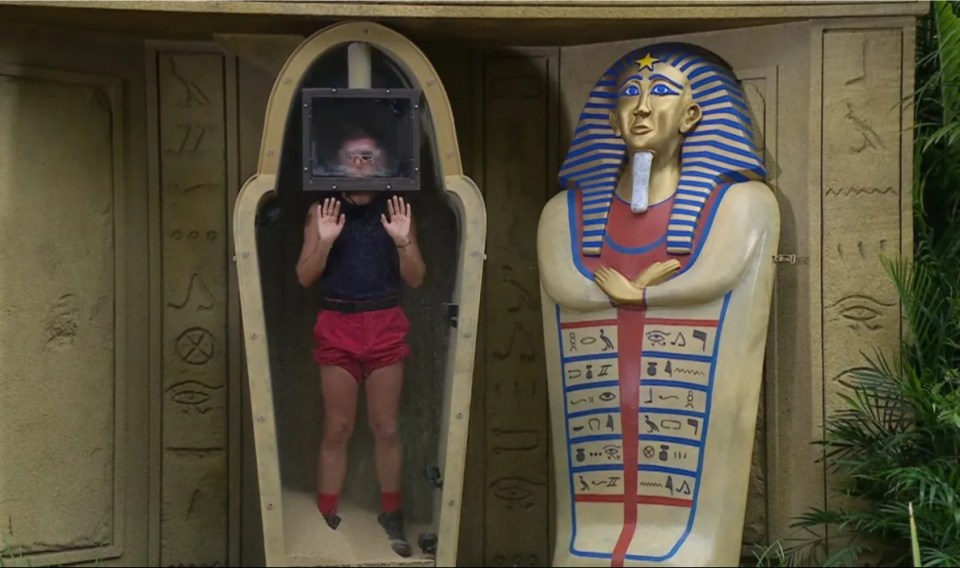 a man is standing in a coffin next to a statue of a pharaoh