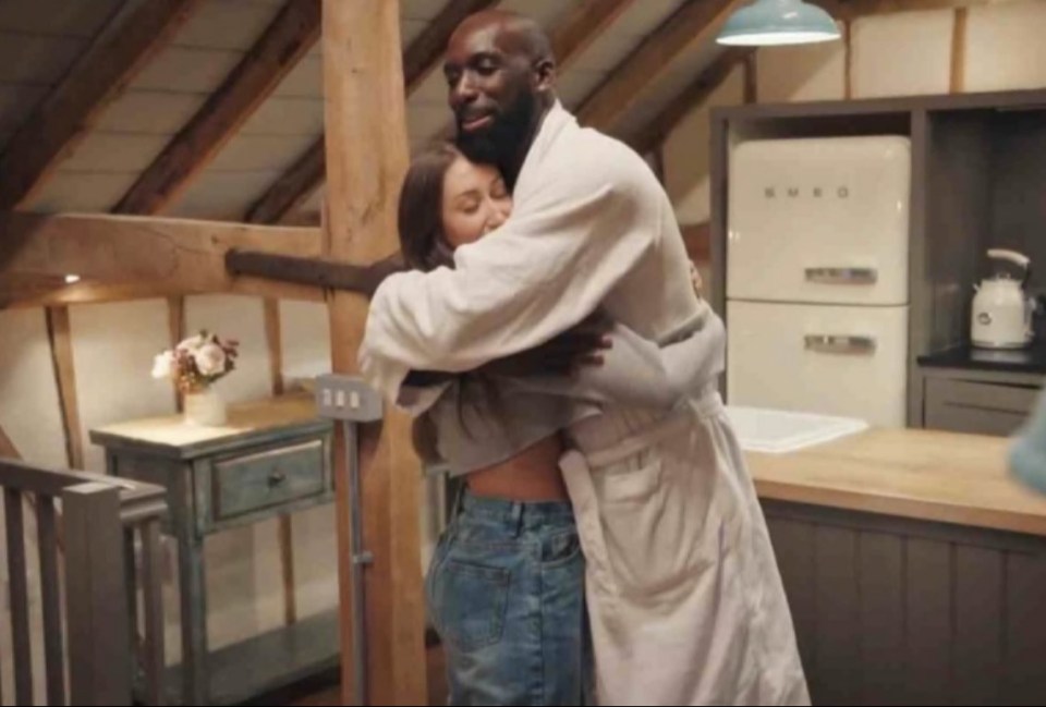 a man in a robe is hugging a woman in a kitchen with a smeg refrigerator in the background