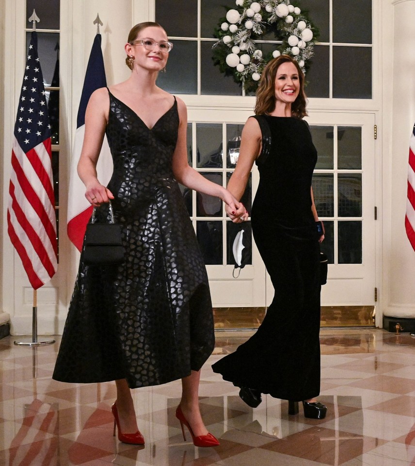 a woman in a black dress holds the hand of another woman