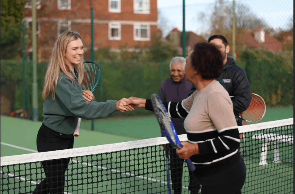 a woman shakes hands with another woman on a tennis court