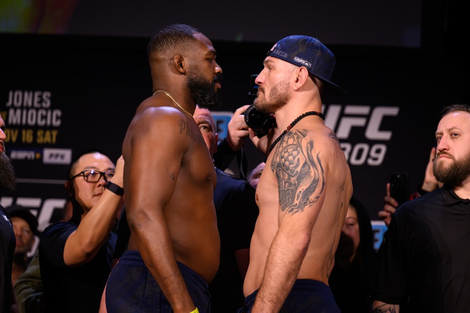 two men are facing each other in front of a sign that says jones miocic