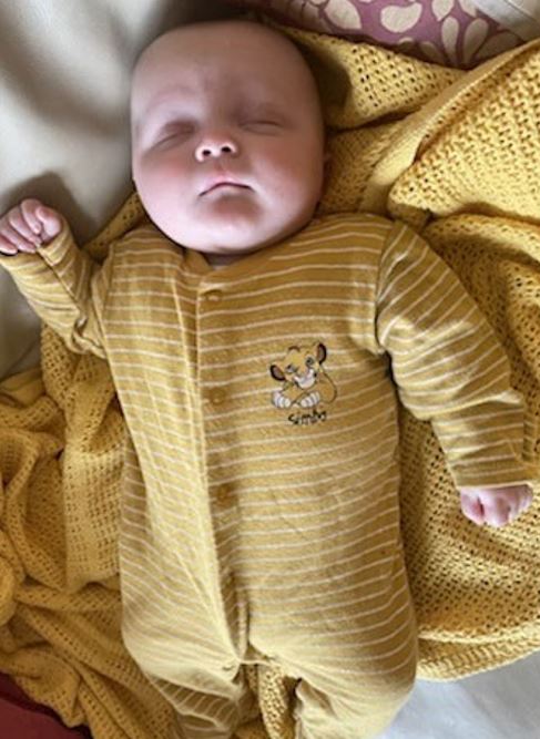 a baby is wearing a yellow striped outfit with a lion on it .