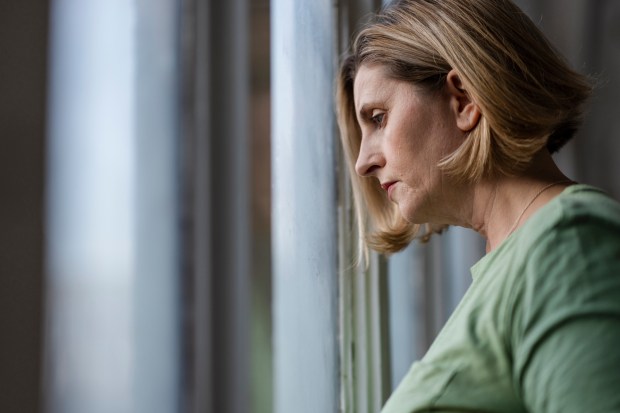 a woman in a green shirt looks out a window