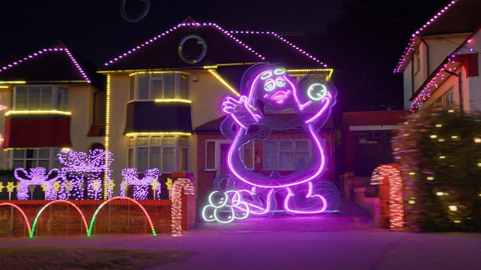 a house is decorated with christmas lights including a purple ghost