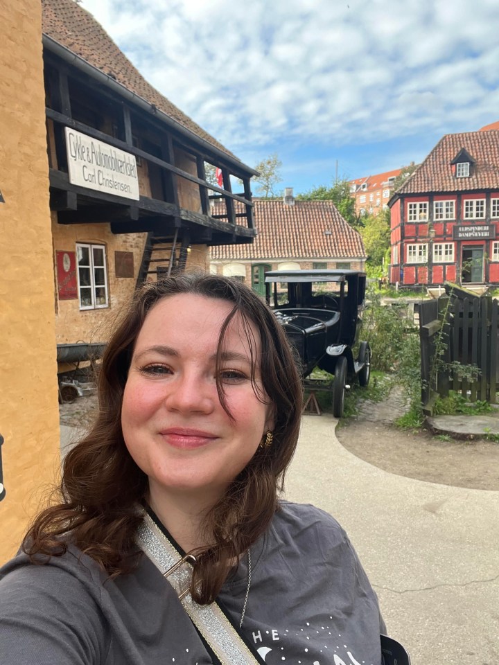 a woman stands in front of a building with a sign that says cafe & automobilhandel