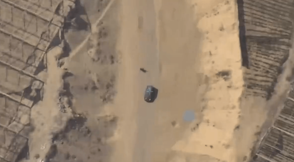 an aerial view of a car driving down a dirt road .