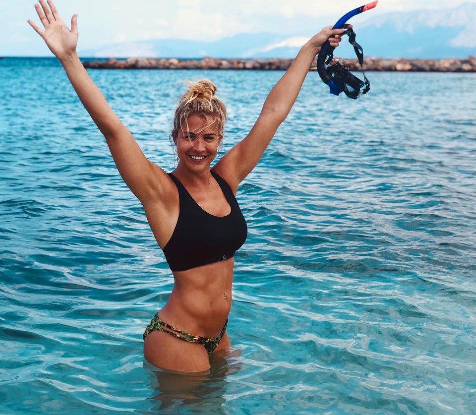 a woman in a bikini is standing in the water with her arms in the air