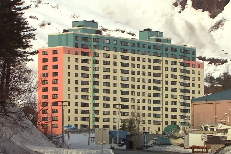 Multi-story apartment building with teal, beige, and coral colored sections.