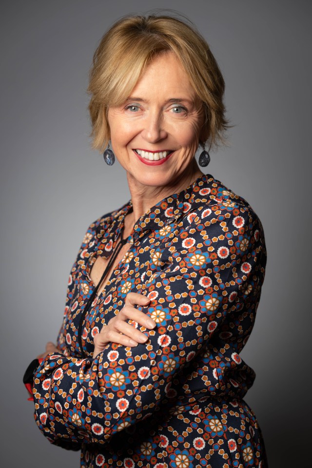 a woman wearing a floral shirt and earrings smiles for the camera