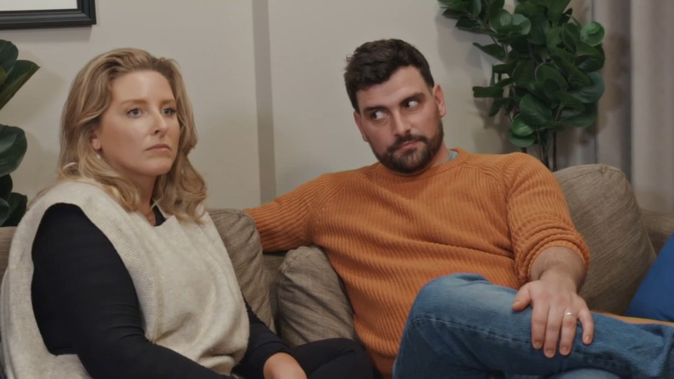 a man and a woman sit on a couch looking at each other