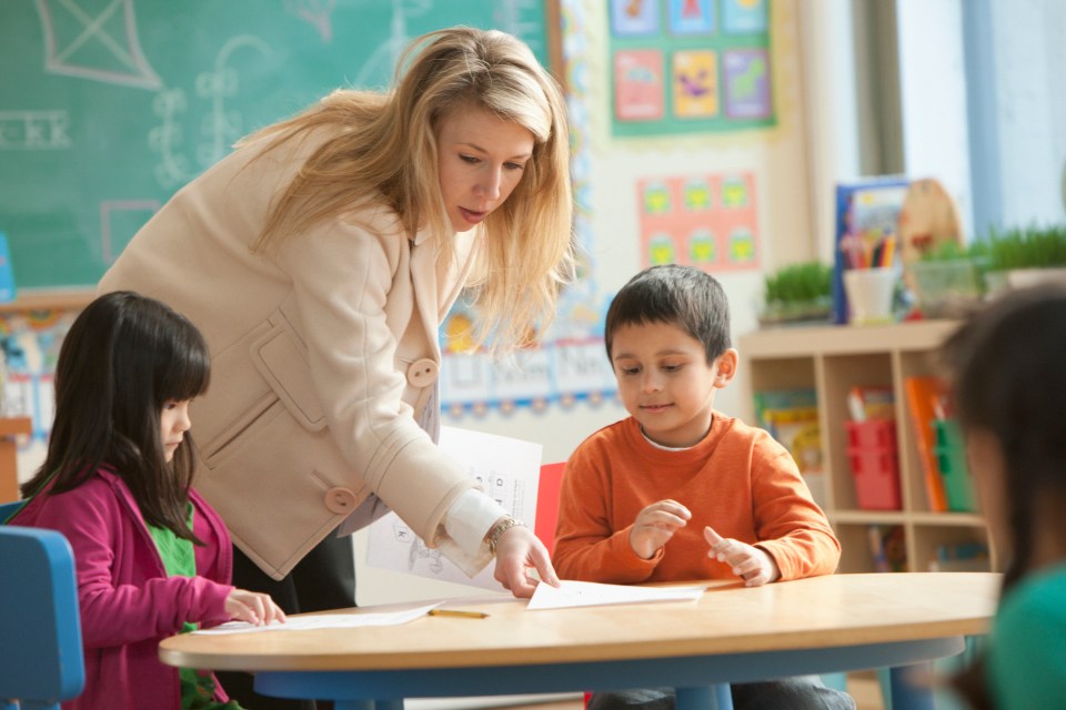 a teacher is pointing at a piece of paper that says ' abc ' on it