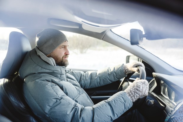 a man wearing a hat and gloves is driving a car