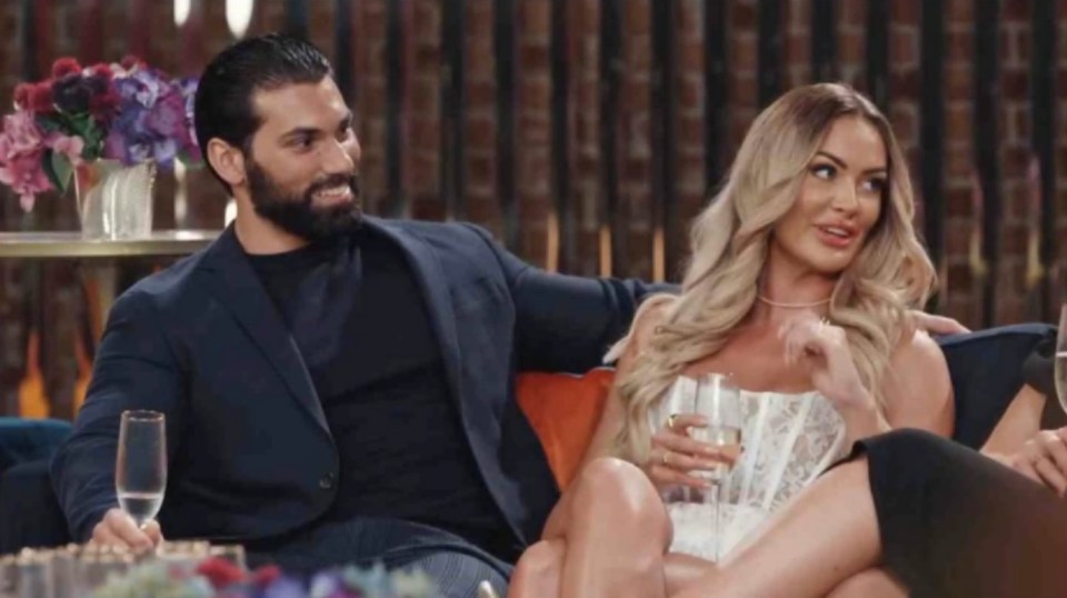 a man and a woman are sitting on a couch holding champagne glasses .