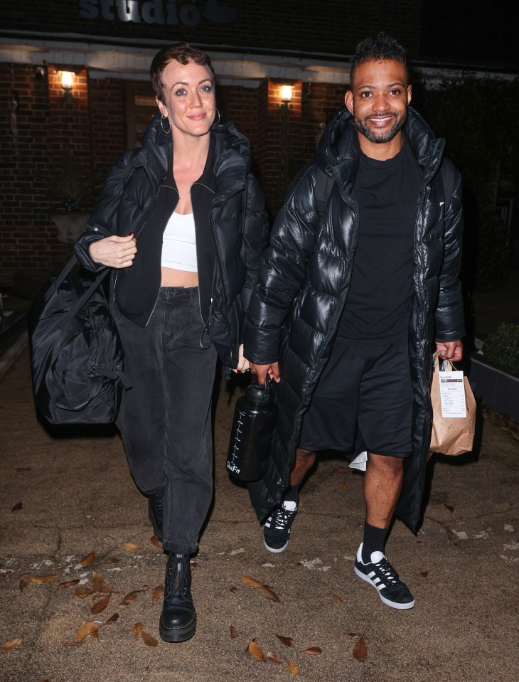 a man and a woman are walking in front of a building that says studios