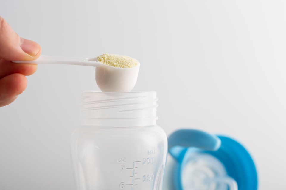 a spoonful of baby food is being poured into a bottle