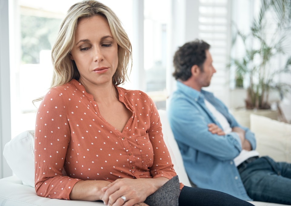 a woman in a polka dot shirt sits next to a man with his arms crossed