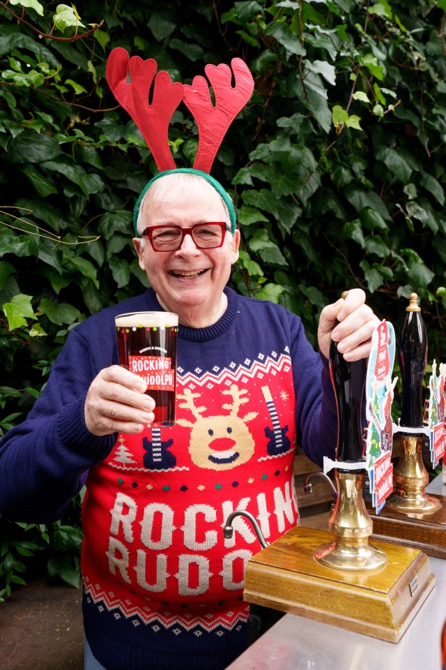 a man wearing a rocking rudolph sweater is pouring a beer