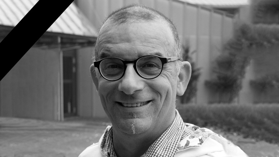 a man wearing glasses is smiling in a black and white photo