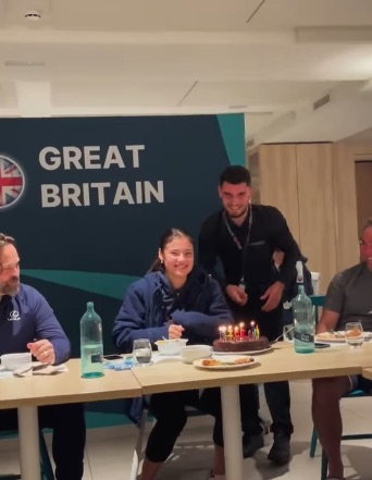 a group of people sitting at a table in front of a wall that says great britain