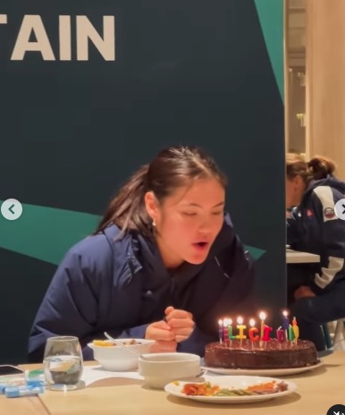 a girl blows out candles on a cake in front of a sign that says " ain "