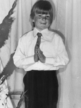 a young boy in a white shirt and tie is praying with his hands folded .