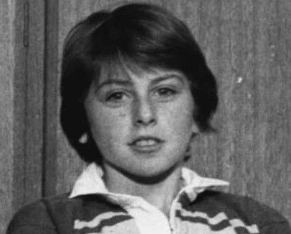 a black and white photo of a young woman wearing a sweater and a white shirt .