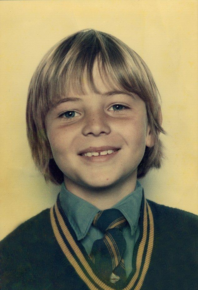 a young boy wearing a sweater and tie smiles for the camera