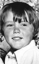 a black and white photo of a young boy smiling for the camera .