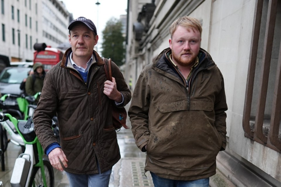 two men are walking down a street with one wearing a hat that says ' liberty ' on it