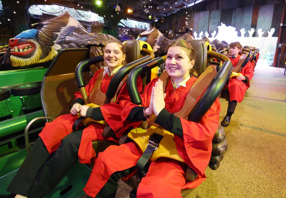 An excited choir group wearing red robes are riding a roller coaster