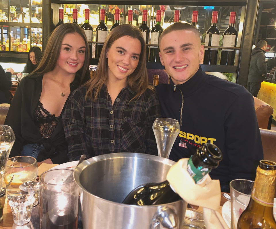 a man wearing a sport ralph lauren shirt sits with two women