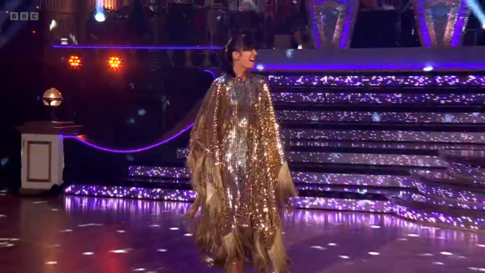 a woman in a gold sequined dress is dancing on a dance floor