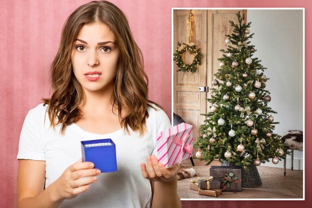 a woman holding a blue box next to a christmas tree