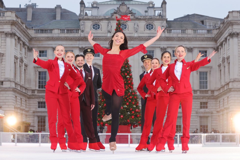 a group of people in red standing in front of a christmas tree