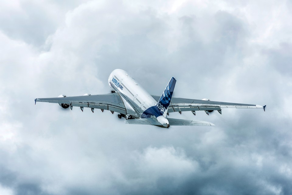 an airbus a380 is flying through a cloudy sky