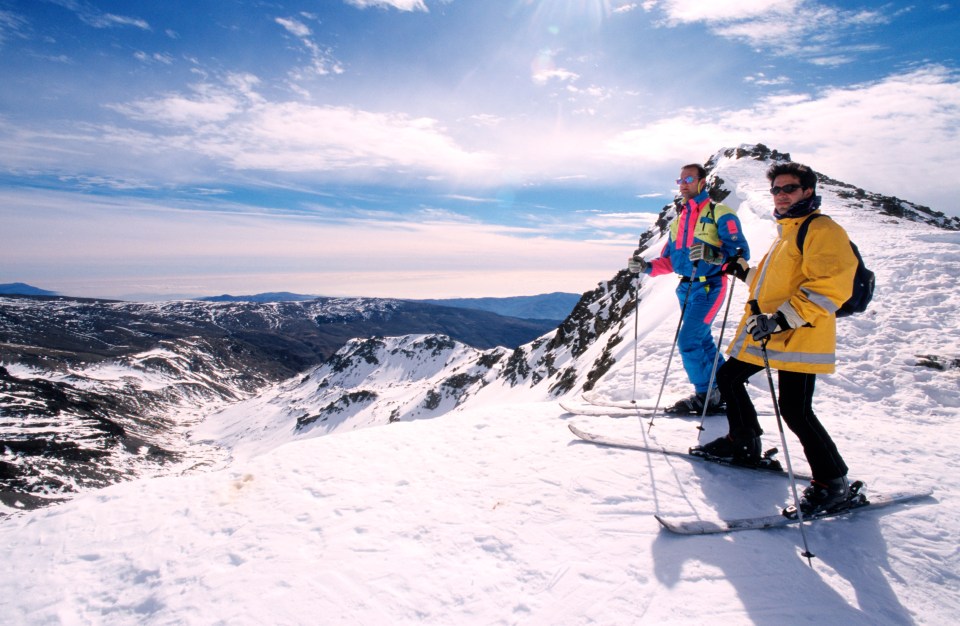 two people standing on top of a snow covered mountain