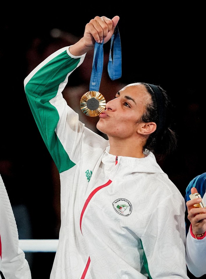 a woman wearing a jacket with the word algeria on it kisses her medal