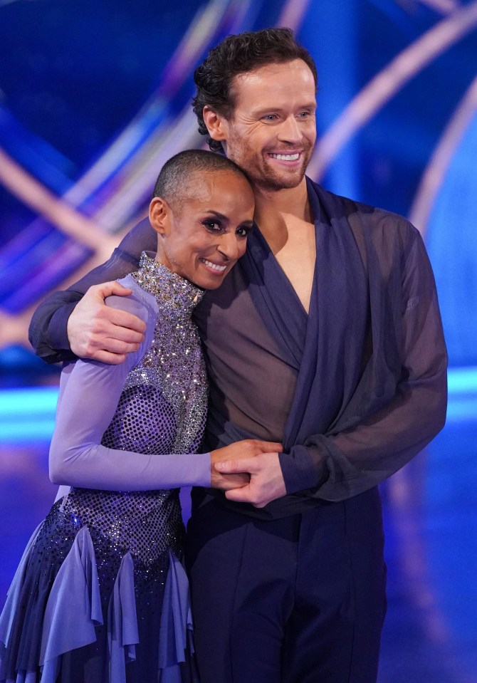 a man and a woman are posing for a picture and the woman has a shaved head